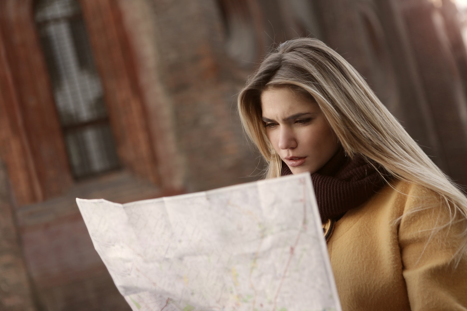 茶色いコートを着た女性が地図を持っている